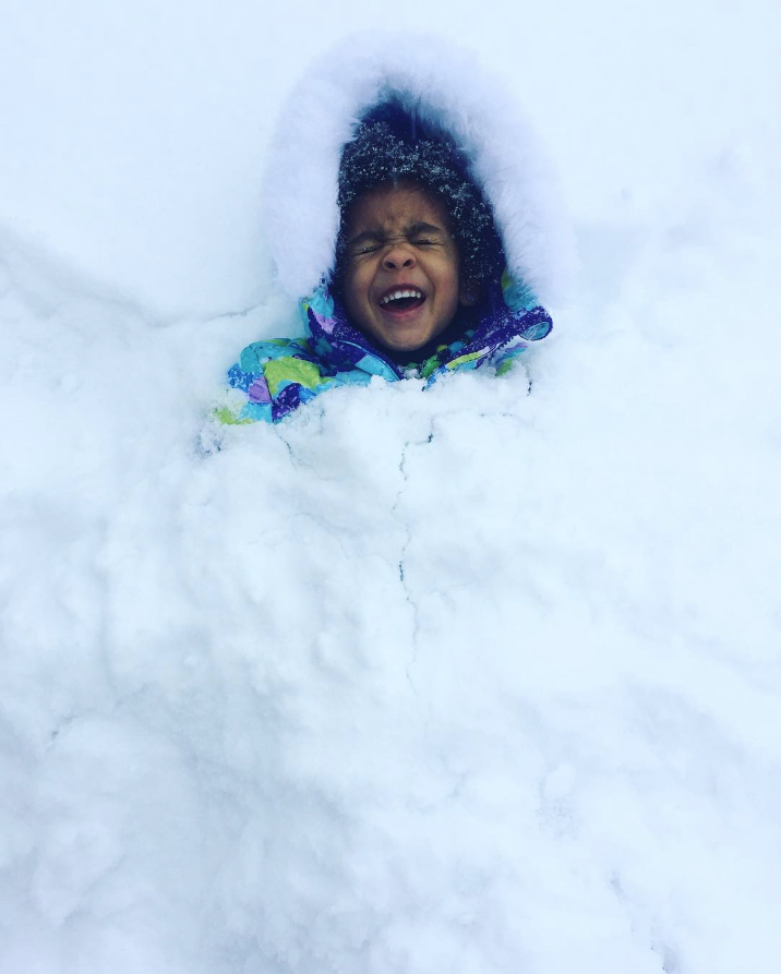 child in snow smiling and laughing